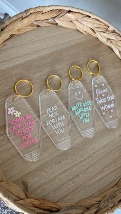 four keychains with different sayings on them sitting on a wooden table next to a basket