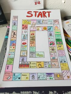 a game board with the words start on it, surrounded by crayons and pencils