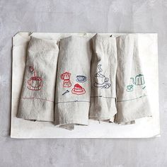 four tea towels are lined up on a towel rack, with coffee cups drawn on them