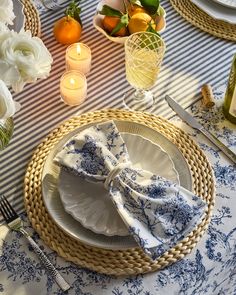 a place setting with blue and white cloths, napkins, silverware and candles