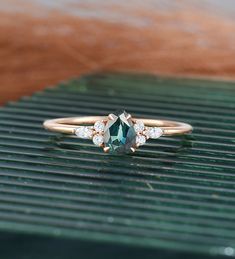 a green and white diamond ring on top of a wooden table with grass in the background