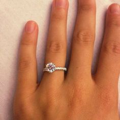 a woman's hand with a diamond ring on top of her left hand,