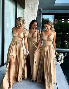 three women in long dresses standing next to each other near a swimming pool and looking at the camera