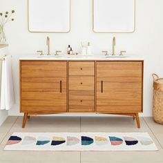 a bathroom with two sinks and mirrors above the sink, along with a rug on the floor