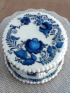 a blue and white decorated cake sitting on top of a cloth covered tablecloth next to a knife