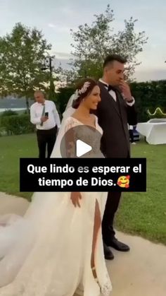 a woman in a wedding dress walking down the sidewalk next to a man wearing a tuxedo