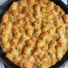 a skillet filled with tater tots and green onions