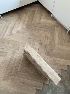 a wooden bench sitting on top of a hard wood floor next to white cupboards