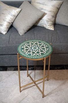 a coffee table sitting on top of a rug next to a gray couch and pillows