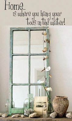 an old window frame sitting on top of a wooden table next to a vase with flowers