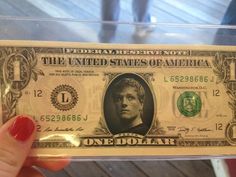 a person holding up a one dollar bill