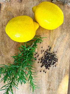 two lemons on a cutting board next to some herbs and peppercorst leaves