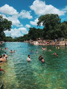 many people are swimming in the water near trees