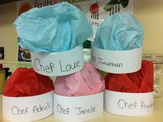 three paper hats with names on them sitting on a counter in front of a sign that says chef louve and chef danielle