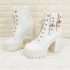 a pair of white high heeled boots with gold buckles