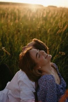 a woman laying in the grass with her eyes closed and looking up at something behind her