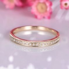 a close up view of a wedding band on a table with flowers in the background