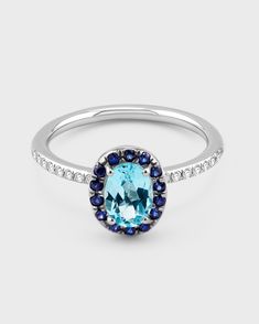 an oval blue topaz ring with diamonds and sapphires on the sides, set in 18k white gold