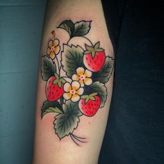 a woman's arm with flowers and strawberries tattooed on the left side of her arm