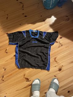 a person standing next to a black and blue shirt on top of a wooden floor