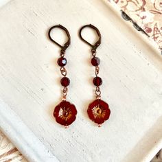 These red flower earrings are a of combination of glass floral beads and vintage red Swarovski crystals creating a beautiful and intricate design. The hand wrapping adds a touch of craftsmanship and attention to detail. The earrings are finished in an antique copper tone, which adds a vintage and rustic feel to the overall look. The matching lever back ear wires provide a secure and comfortable fit while ensuring the earrings hang elegantly. The red color scheme and floral elements give off a vi Red Beaded Flower Shaped Jewelry, Elegant Red Czech Glass Earrings, Red Garnet Wire Wrapped Earrings, Elegant Red Czech Glass Beaded Earrings, Red Beaded Czech Glass Earrings, Vintage Red Beaded Earrings As Gift, Vintage Red Beaded Earrings For Gift, Elegant Red Beaded Flower Earrings, Vintage Red Flower Shaped Jewelry