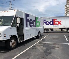 a fedex truck parked in a parking lot next to a large white box truck