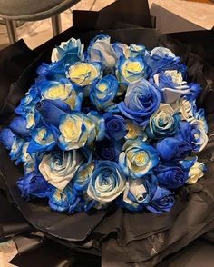 a bouquet of blue and white roses in a black paper wrapper