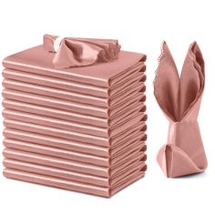 a stack of folded pink napkins next to a bow - knoted napkin holder