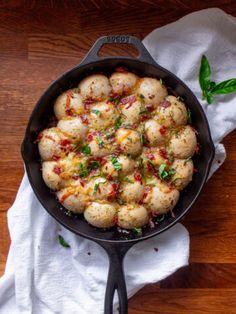 a skillet filled with food sitting on top of a wooden table next to a white towel