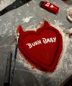 a heart shaped cake sitting on top of a table next to knifes and paint