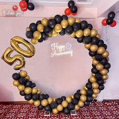 the balloon arch is decorated with black, gold and red balloons