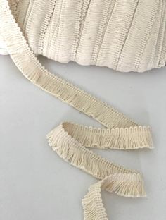 a white purse with fringes on the bottom and side, sitting on top of a table