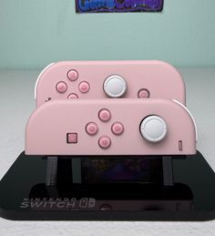 a pink nintendo wii controller sitting on top of a black stand