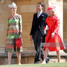 two women and a man are standing in front of an old building wearing colorful outfits