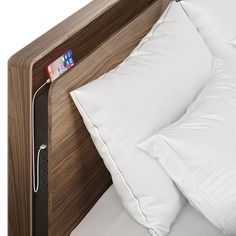 a bed with white pillows and a wooden headboard that has an ipod plugged into it