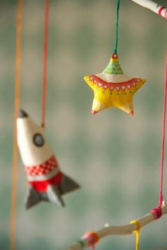 three colorful ornaments hanging from strings in the shape of rockets