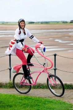 a woman is riding a pink bike on the street