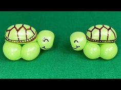 two green turtle figurines sitting next to each other on top of a green surface