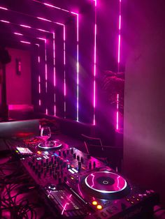 a dj set up in front of a mirror with neon lights