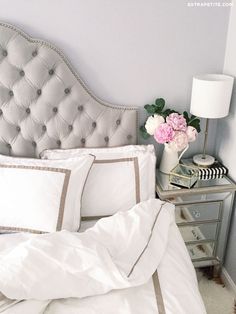 a bed with white linens and pillows in a bedroom next to a night stand