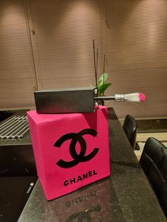 a pink chanel box sitting on top of a table next to a black chair