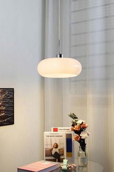 a glass table topped with a vase filled with flowers next to a wall mounted light