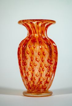 an orange glass vase sitting on top of a table