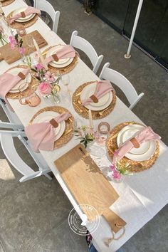 the table is set with pink and white plates, napkins, and place settings