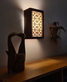 a lamp that is on the side of a wall next to a vase with a bird in it