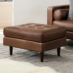 a brown leather ottoman sitting on top of a rug