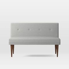 an upholstered bench with wooden legs and buttons on the armrests is shown in front of a white background