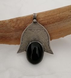 A great Berber Tuareg Khamsa pendant reinterpreted. Featuring the inverted Khamsa / Hand of Fatima, with a large piece of onyx set in place of the central 3 fingers. The large oval cabochon is polished to a high shine and is framed by hand carved silver accented with niello pigment..  The carvings are in the traditional Tuareg geometry of triangles, parallel lines and curves (symbolising nomadic tents, drifting desert sands & animal tracks).  In the Tuareg tradition, silver-smithing is man's work and being a nomadic people, their jewelry is multifunctional by necessity: simultaneously decorative, talismanic and practical.  Weight: 22,5 grams Shipping : DHL EXPRESS 🙂 Traditional Black Engraved Necklace, Traditional Black Medallion Necklace, Artisan Black Ceremonial Jewelry, Artisan Black Engraved Necklace, Traditional Black Medallion Shaped Jewelry, Traditional Black Necklaces With Large Pendant, Traditional Black Necklace With Large Pendant, Animal Tracks, Parallel Lines