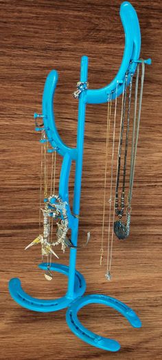 a blue sculpture on top of a wooden table with jewelry hanging from it's sides