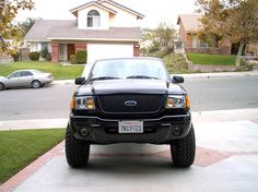 a black truck parked in front of a house on the side of a road next to a driveway